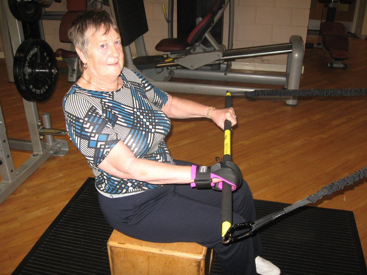 Mujer mayor entrenando con banda elástica usando agarre adaptativo Active Hands. Garra Adaptive Argentina.