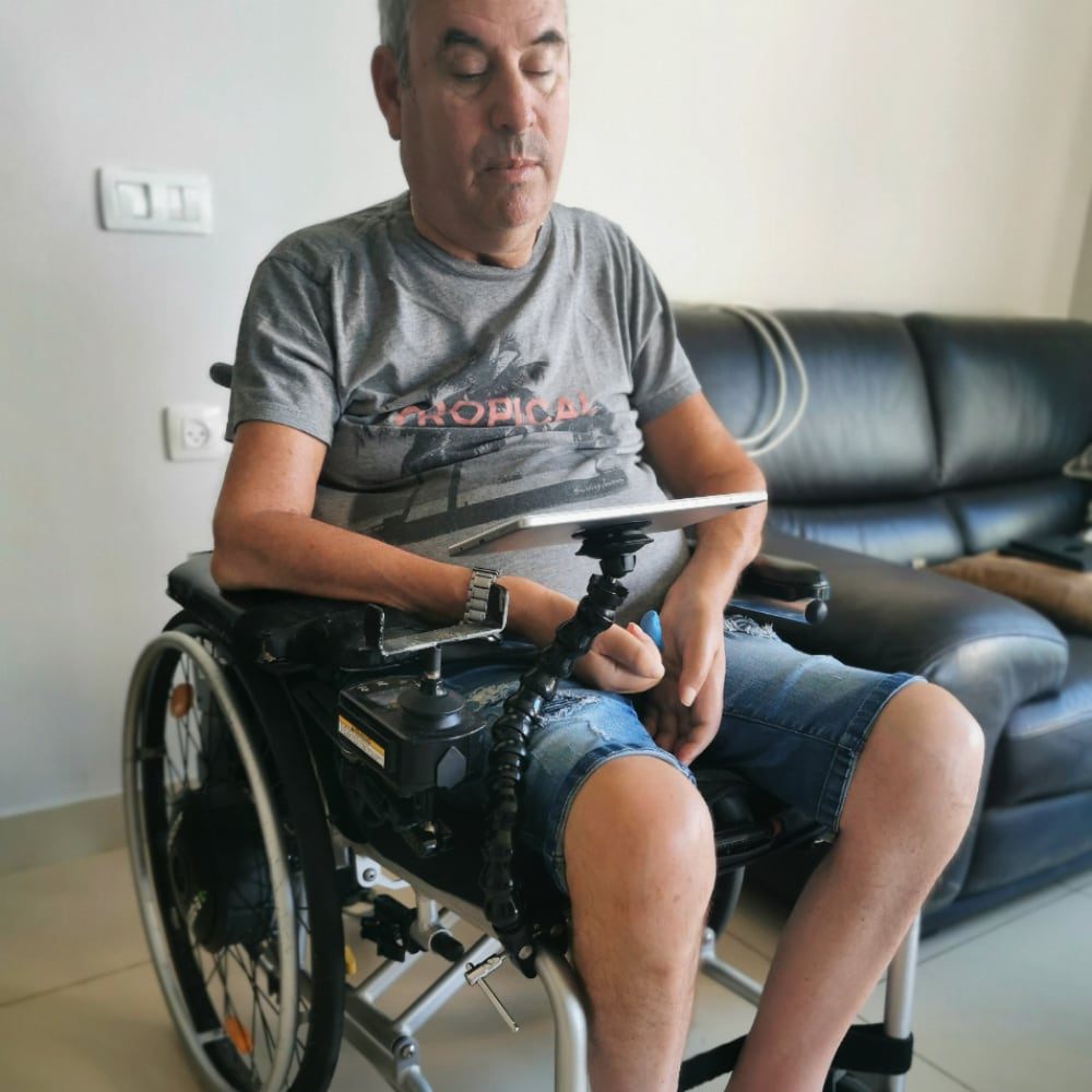 Persona en silla de ruedas usando el soporte flexible para tablet Active Hands. Garra Adaptive Argentina.