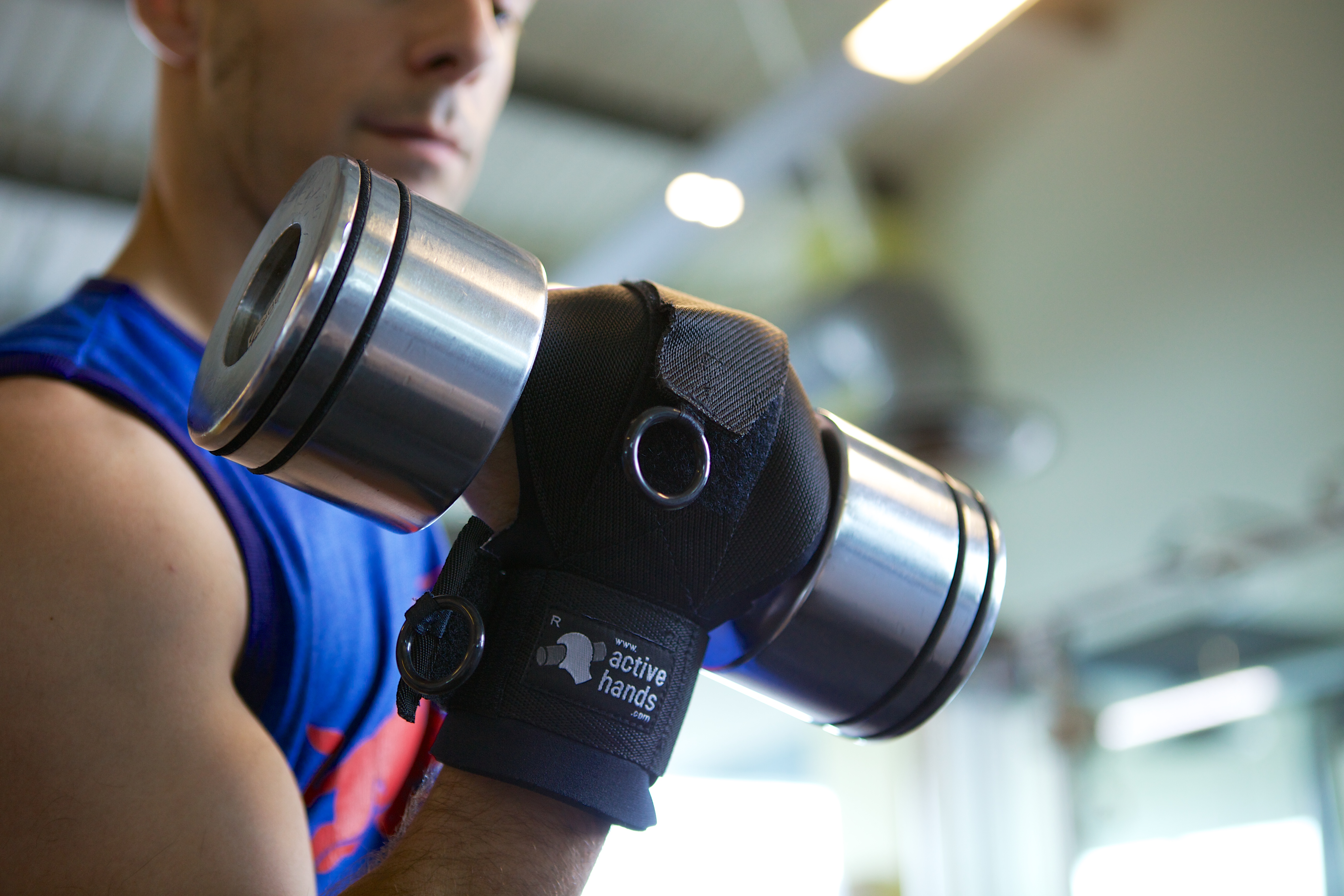 Persona entrenando con mancuernas usando el agarre de uso general Active Hands en el gimnasio. Producto adaptativo para función reducida de la mano: lesión medular, ACV, parálisis cerebral. Garra Adaptive Argentina.